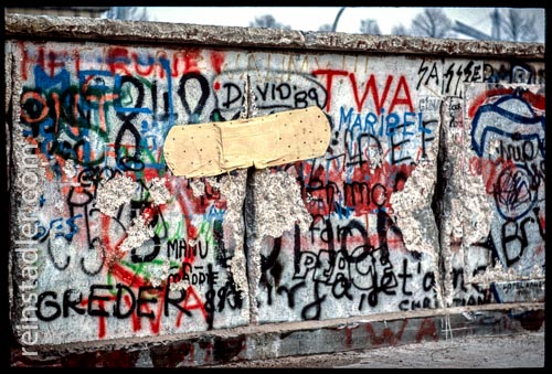  Ein großes Pflaster über einem Riss auf der mit Graffitis bedeckten Berliner Mauer im Winter 1989. 